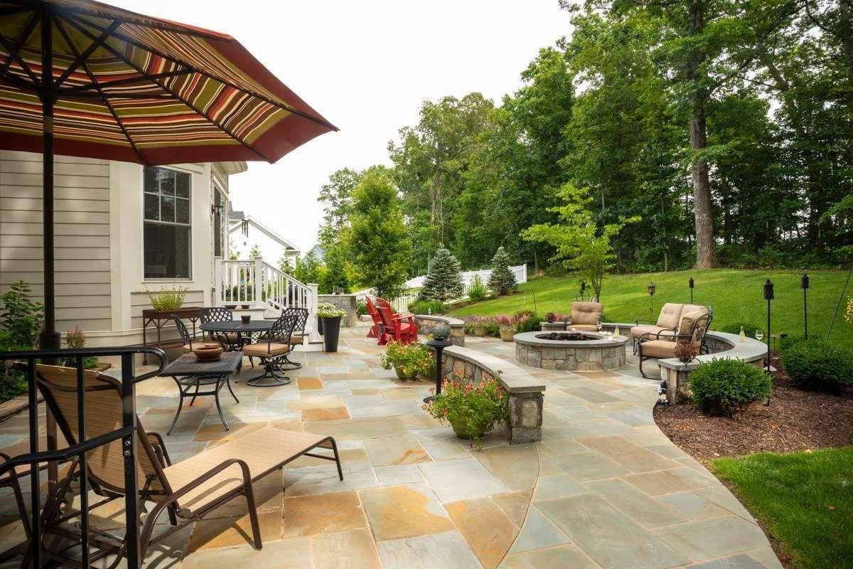 A stone fire pit set into flagstone, with a low seat wall wrapping the sitting area.