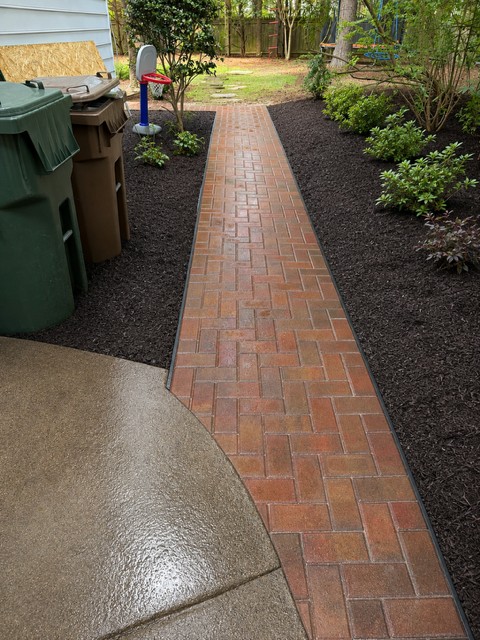 The finished brick walkway with mulched beds and new shrubs planted along both sides.